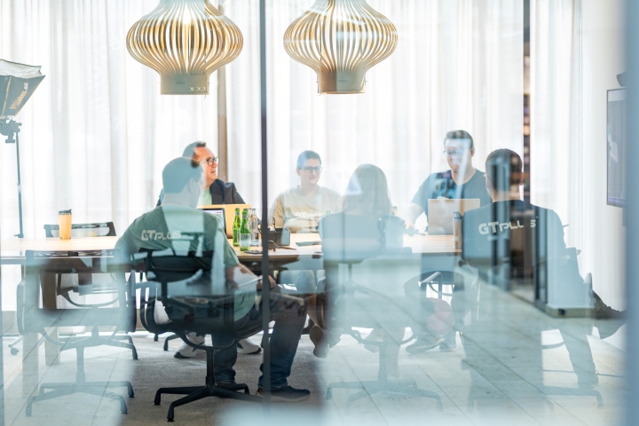 Mitarbeiter von GT-Plus arbeiten gemeinsam im Meeting-Raum.